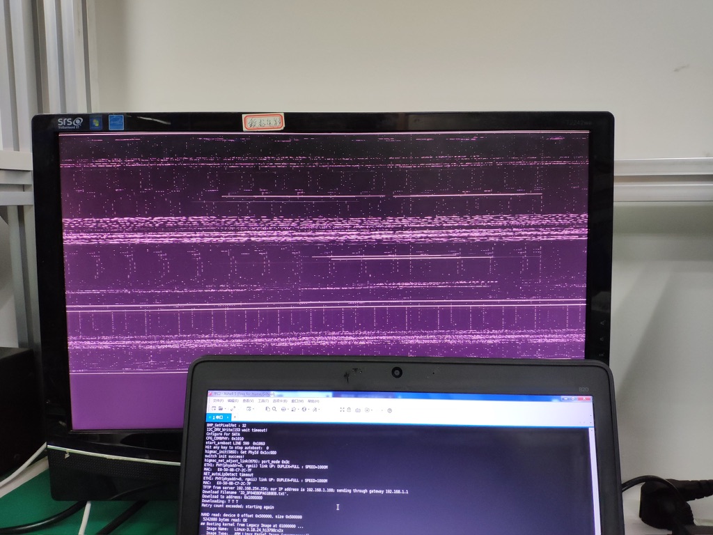 An external monitor showing purple display noise with a laptop terminal in front.