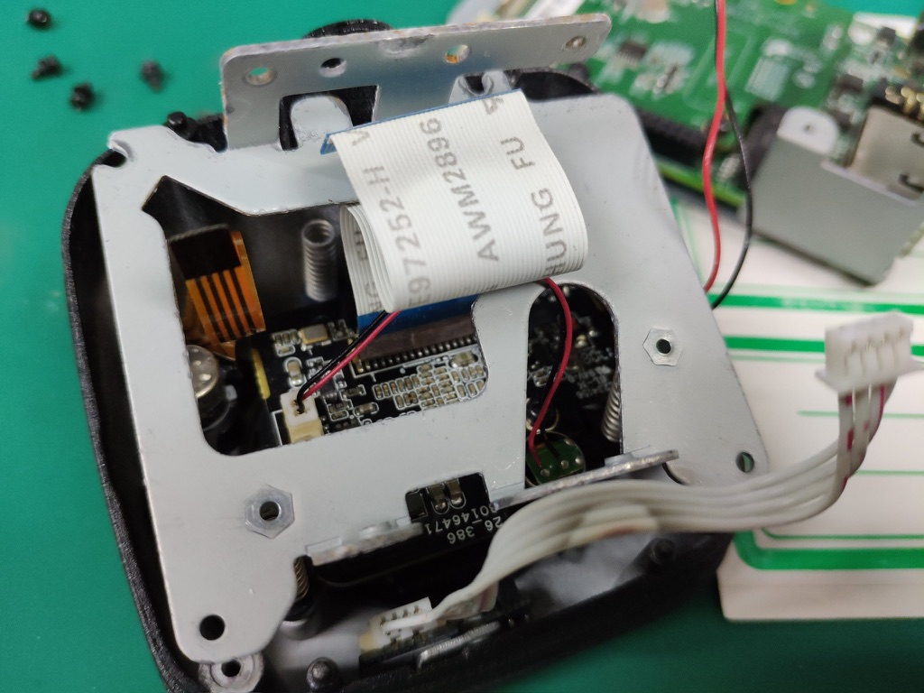 The inside of a disassembled robot car with ribbon cables, brackets, and circuit boards.